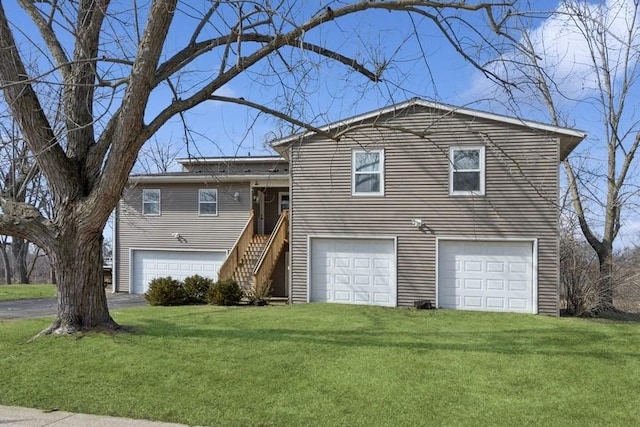 tri-level home with a front lawn, stairway, a garage, and driveway