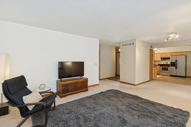 unfurnished living room with light carpet, visible vents, a textured ceiling, and baseboards