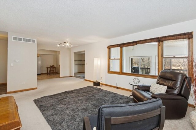 carpeted living room with visible vents, baseboards, and a textured ceiling