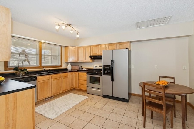 kitchen featuring dark countertops, visible vents, under cabinet range hood, appliances with stainless steel finishes, and a sink