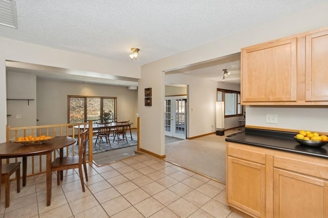 kitchen featuring a textured ceiling, dark countertops, and light brown cabinetry