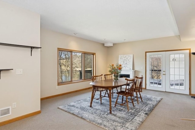 dining area with visible vents, french doors, carpet, a lit fireplace, and baseboards