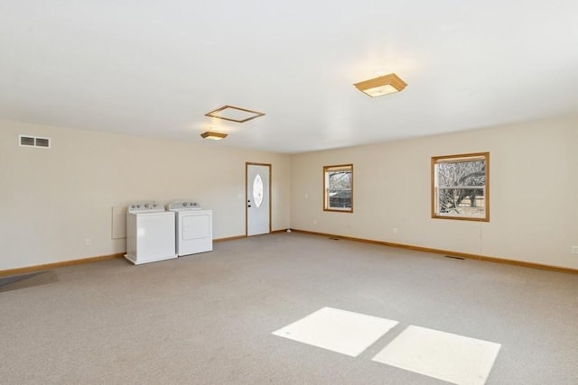 carpeted spare room with visible vents, baseboards, and washing machine and dryer