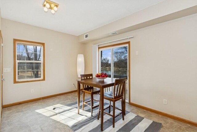 dining area with baseboards, visible vents, and arched walkways