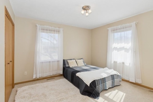 bedroom with visible vents, baseboards, and light carpet