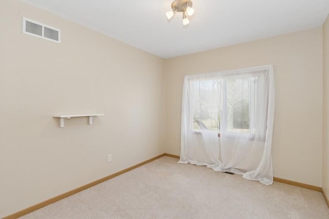 empty room featuring visible vents, baseboards, and light colored carpet