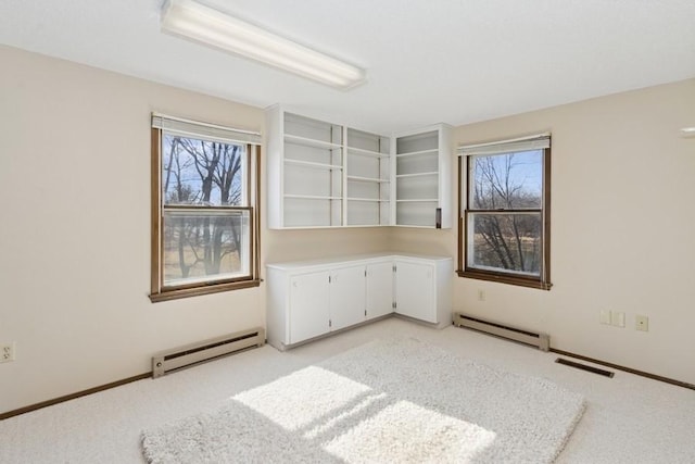 spare room featuring plenty of natural light, light colored carpet, and baseboard heating