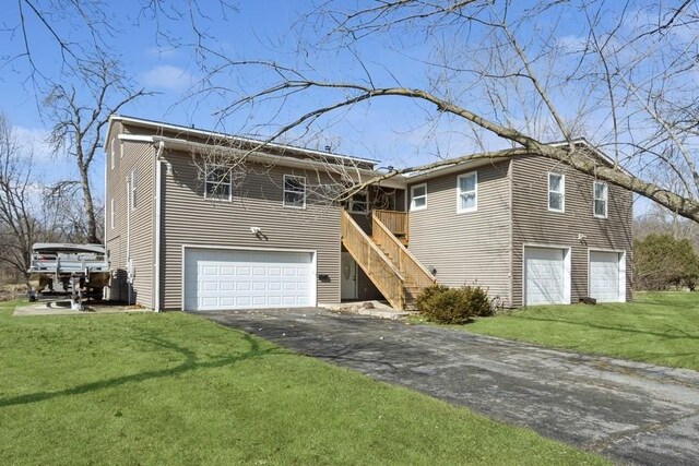 view of front of house featuring stairs, aphalt driveway, a front yard, and an attached garage