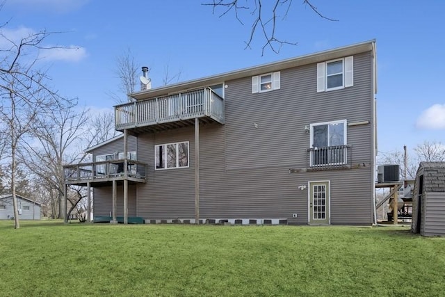 rear view of house with central AC unit, a balcony, and a lawn