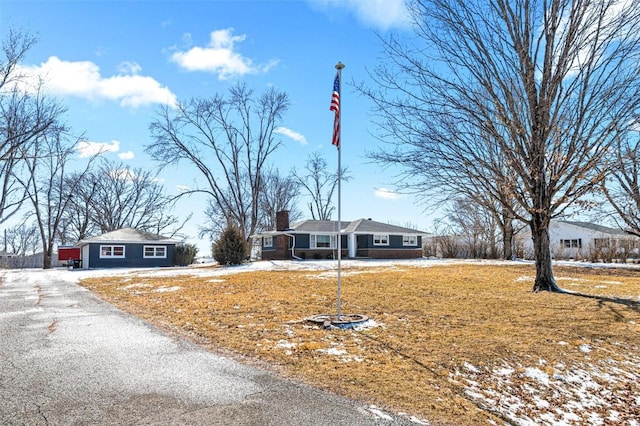 view of front of home with aphalt driveway, a chimney, and a front lawn