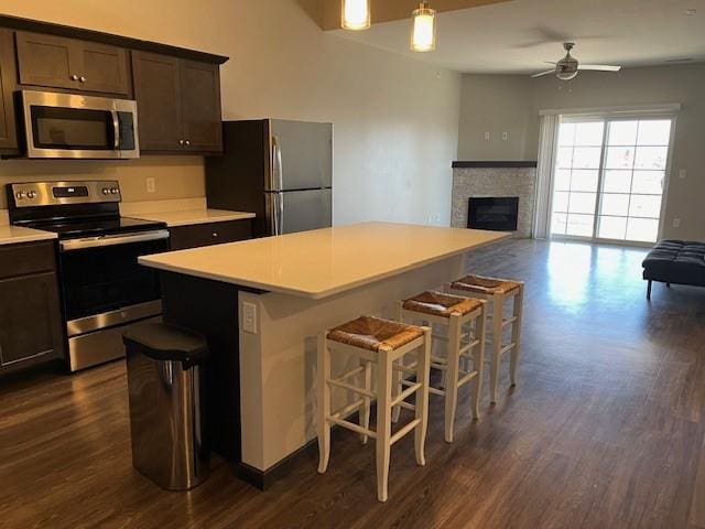 kitchen featuring a kitchen island, appliances with stainless steel finishes, open floor plan, and dark wood-style flooring