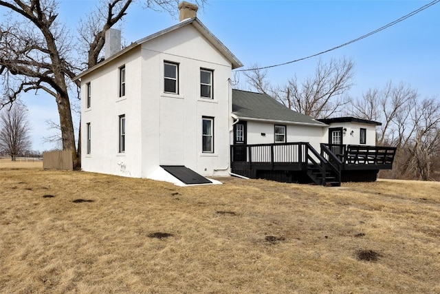 rear view of property featuring a wooden deck, a yard, and a chimney