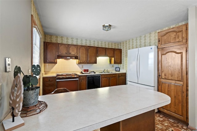 kitchen featuring wallpapered walls, electric range, freestanding refrigerator, a sink, and black dishwasher