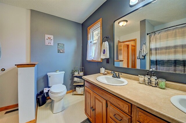 bathroom featuring visible vents, double vanity, a sink, a textured ceiling, and toilet