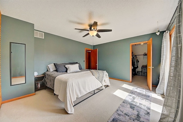 carpeted bedroom featuring a walk in closet, baseboards, visible vents, and a textured ceiling