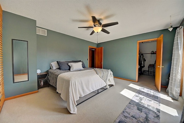 carpeted bedroom with a spacious closet, baseboards, visible vents, and a textured ceiling