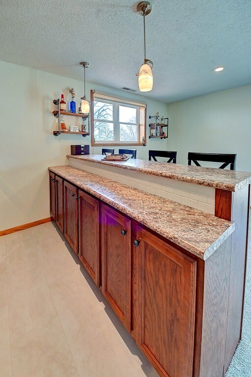 kitchen featuring decorative light fixtures, a peninsula, a textured ceiling, and baseboards