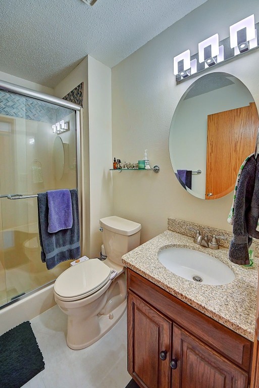 bathroom with vanity, toilet, a stall shower, and a textured ceiling