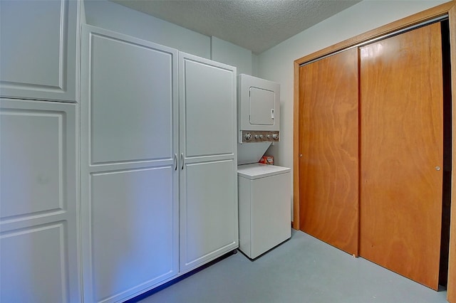 washroom with stacked washer and dryer and a textured ceiling