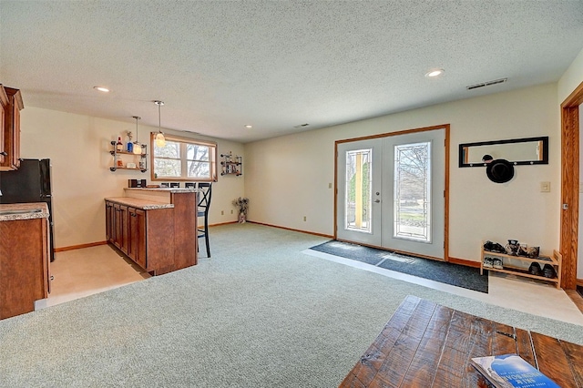 kitchen featuring visible vents, brown cabinets, a kitchen breakfast bar, french doors, and a peninsula