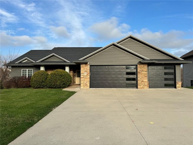 view of front of property with stone siding, a garage, driveway, and a front lawn