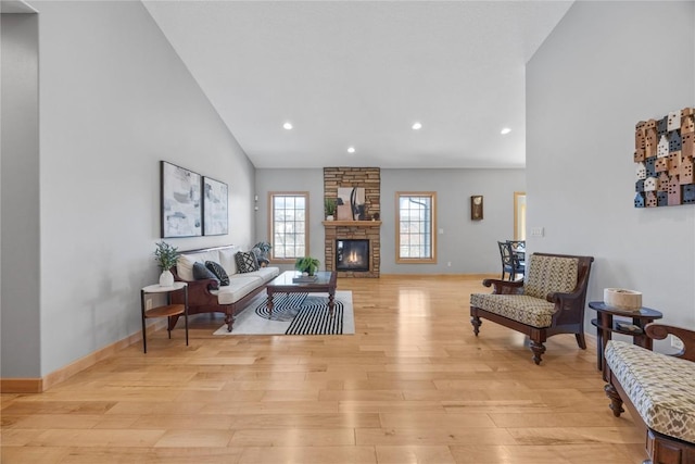 living area with recessed lighting, a fireplace, high vaulted ceiling, and light wood-style floors