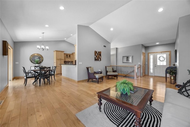 living room with lofted ceiling, an inviting chandelier, baseboards, and light wood finished floors