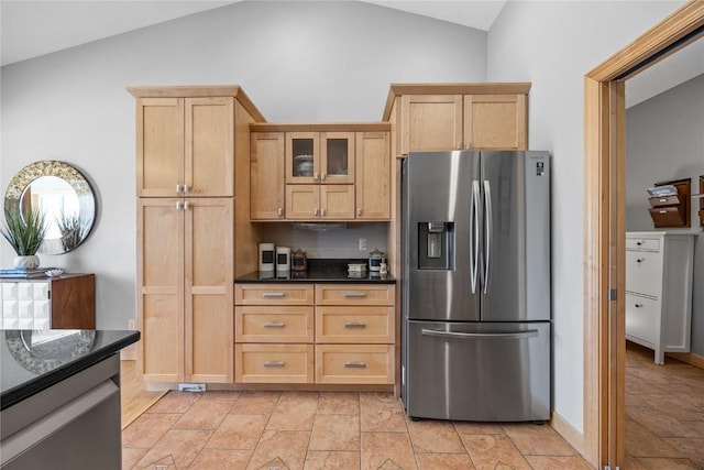 kitchen with lofted ceiling, glass insert cabinets, light brown cabinets, and stainless steel fridge