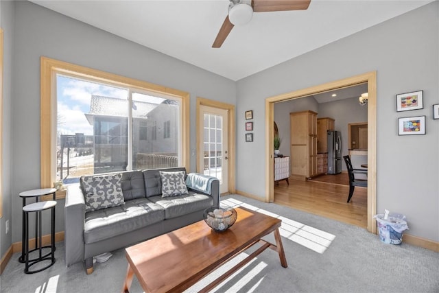 living room featuring a ceiling fan, baseboards, and light wood-type flooring