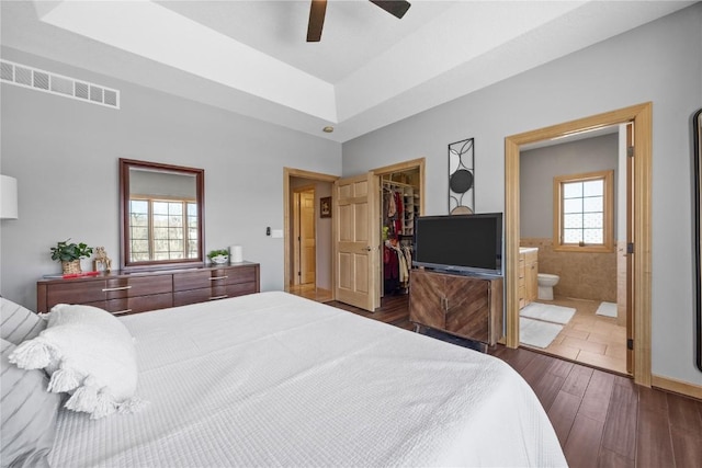 bedroom featuring visible vents, a walk in closet, wood finished floors, a closet, and ensuite bath