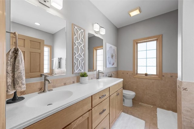 bathroom with a sink, tile walls, tile patterned floors, and a healthy amount of sunlight