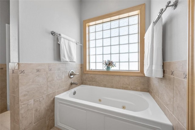 full bath with a tub with jets, tile walls, and a wainscoted wall