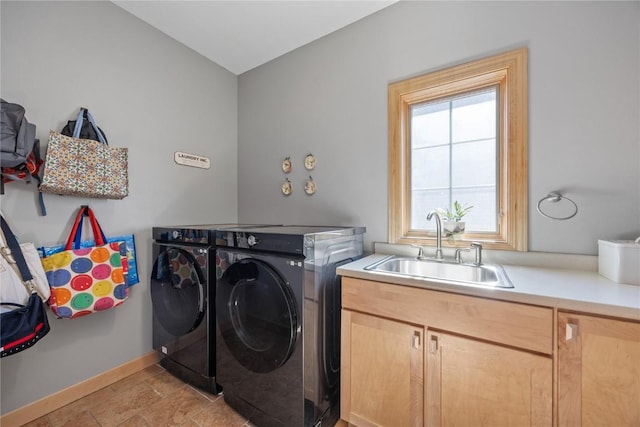 laundry room with cabinet space, washer and dryer, baseboards, and a sink