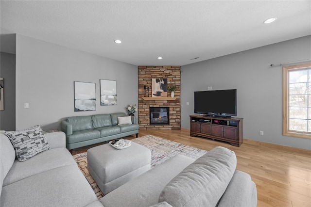 living area featuring recessed lighting, a fireplace, light wood finished floors, and a textured ceiling