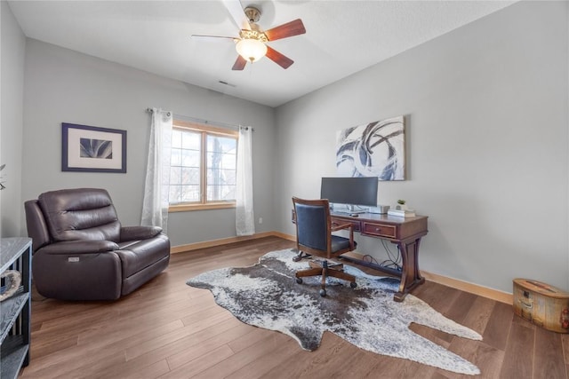 home office with visible vents, wood finished floors, baseboards, and ceiling fan