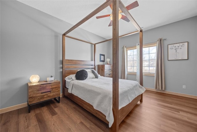 bedroom with a ceiling fan, lofted ceiling, wood finished floors, and baseboards