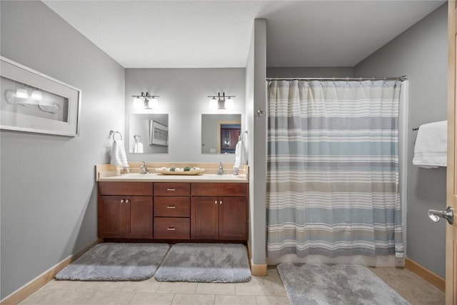 bathroom with a sink, baseboards, and double vanity