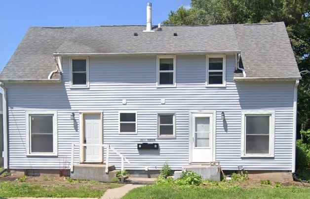 rear view of property with a shingled roof and entry steps