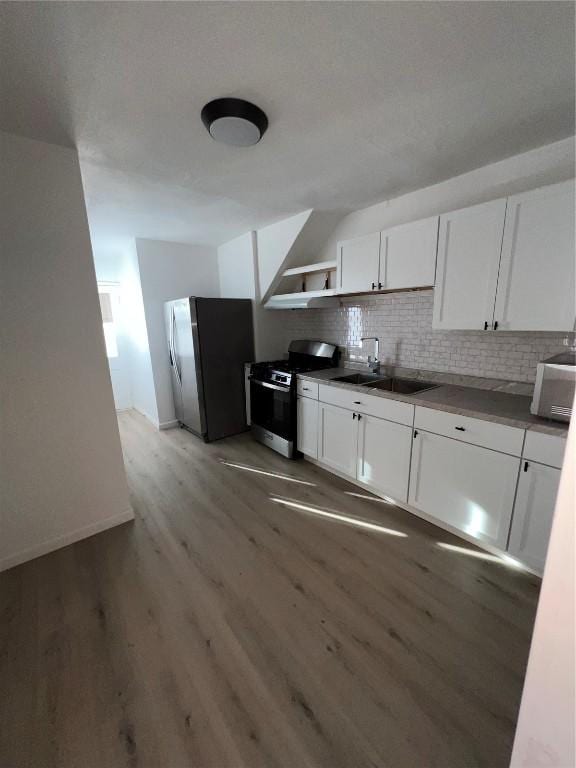 kitchen featuring gas stove, freestanding refrigerator, a sink, white cabinets, and light wood-style floors