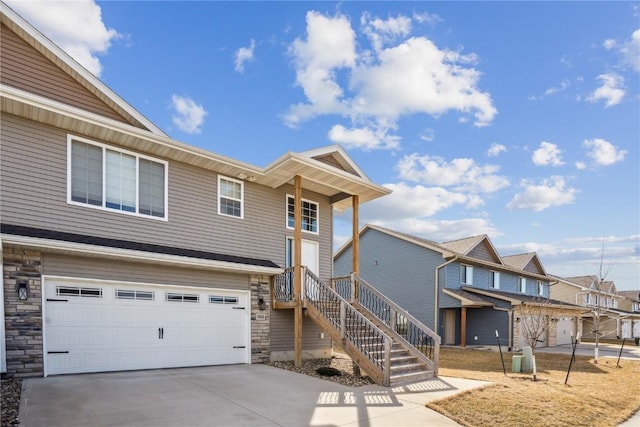 multi unit property with driveway, stone siding, stairway, a residential view, and an attached garage