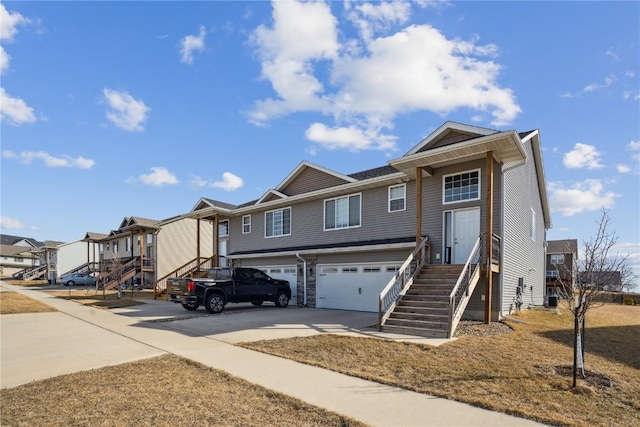 view of front of home with a garage, a residential view, concrete driveway, and stairway