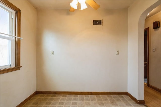 empty room featuring visible vents, baseboards, arched walkways, and ceiling fan