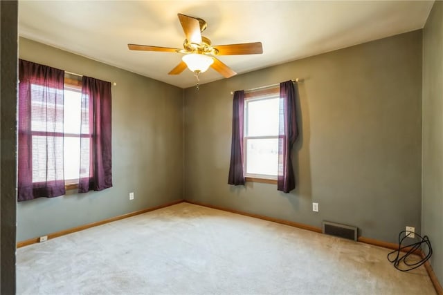 empty room with visible vents, a healthy amount of sunlight, and carpet flooring