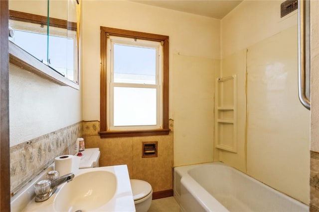 bathroom with shower / washtub combination, toilet, and a sink