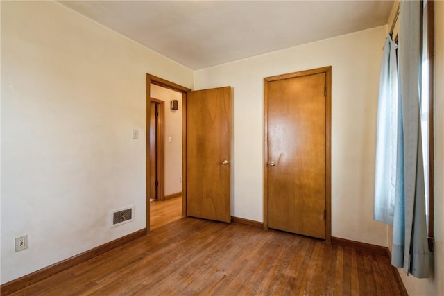 unfurnished bedroom with visible vents, baseboards, and wood finished floors