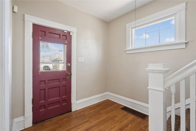 foyer entrance featuring visible vents, stairway, baseboards, and wood finished floors