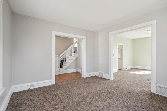 carpeted empty room featuring visible vents and baseboards