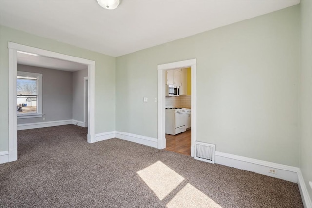 unfurnished room with carpet flooring, baseboards, and visible vents