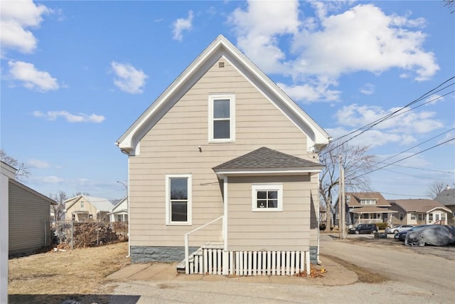 back of house with a residential view and a shingled roof