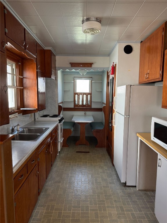 kitchen featuring brown cabinets, white appliances, light countertops, and a sink